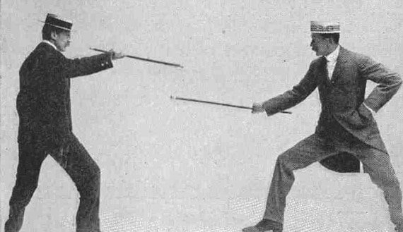 Foto antigua de dos hombres peleando con sus bastones. 